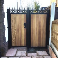 A bespoke steel frame gate with ornate ironwork and timber infill, fitted with matching side panels in Wigan, North West.